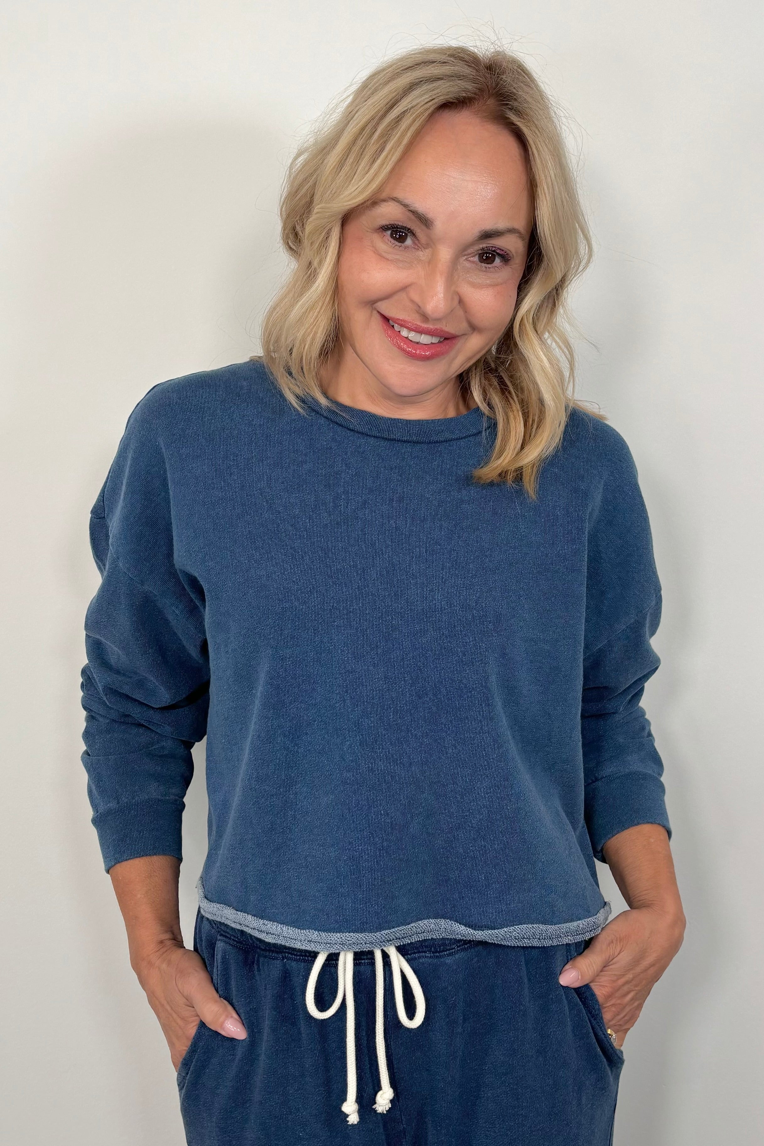 Woman wearing a blue sweatshirt and matching pants with a white background
