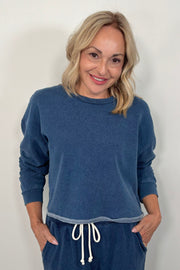 Woman wearing a blue sweatshirt and matching pants with a white background