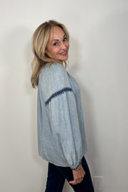 Side view of woman wearing a blue tencel blouse with stitch detailing