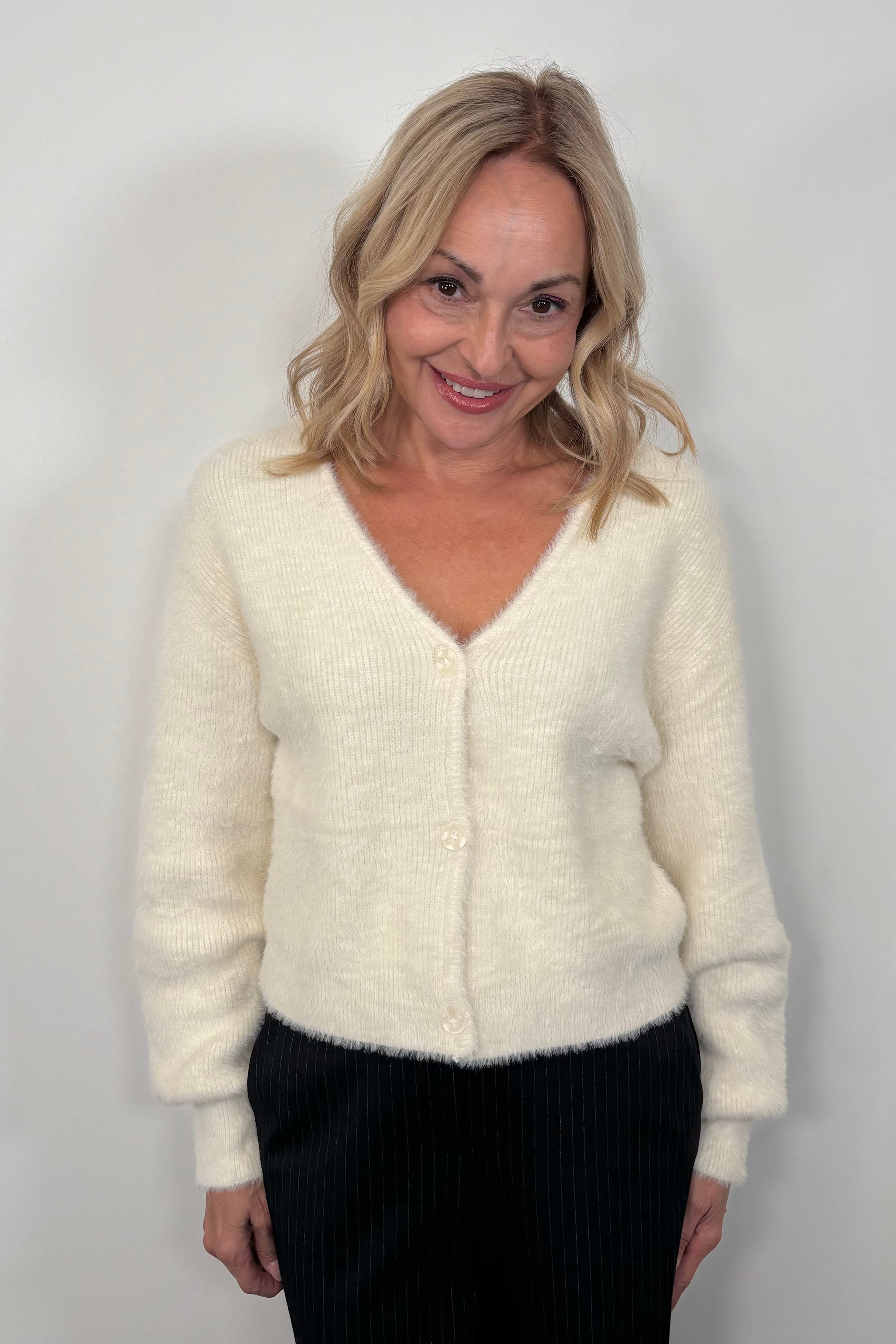 Woman wearing a cream cardigan against a plain background