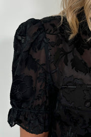 Close-up of the shoulder of a black burnout short sleeve shirt