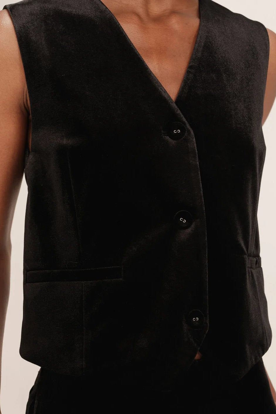 Black velvet vest worn by a person on a beige background