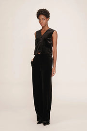 Person wearing a black sleeveless top and black pants on a white background