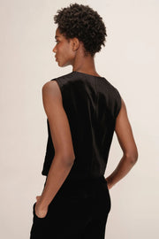Woman wearing a black sleeveless top against a plain background