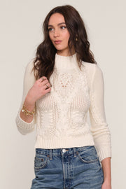 Front view of a woman wearing a cream-colored cable knit sweater