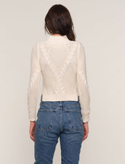Back view of a woman wearing a cream-colored cable knit sweater