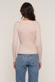 Back facing woman wearing an oat coloured long sleeve ribbed top.