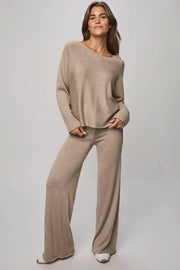 Woman wearing a beige sweater and pants set on a plain background