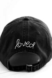 Black cap with 'loved' embroidery on a white background
