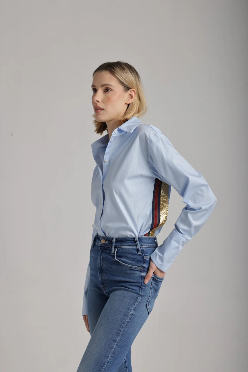 Side view of woman wearing a light blue shirt with red, navy and gold sequence stripes on the side