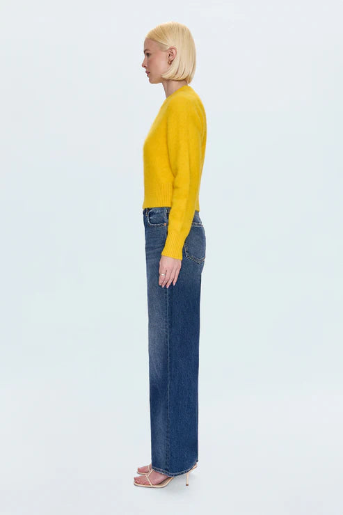 Person wearing a yellow sweater and blue jeans on a white background
