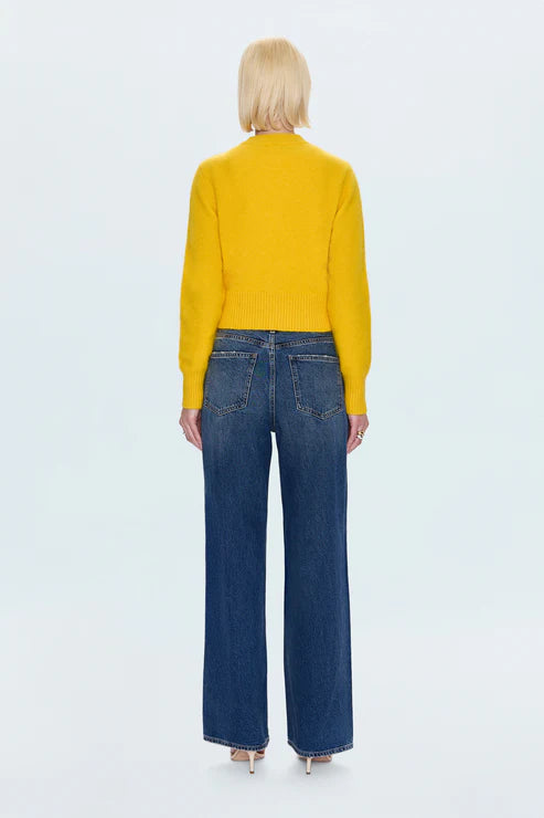 Person wearing a yellow sweater and blue jeans on a white background