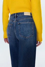 Person wearing blue jeans and a yellow sweater on a white background