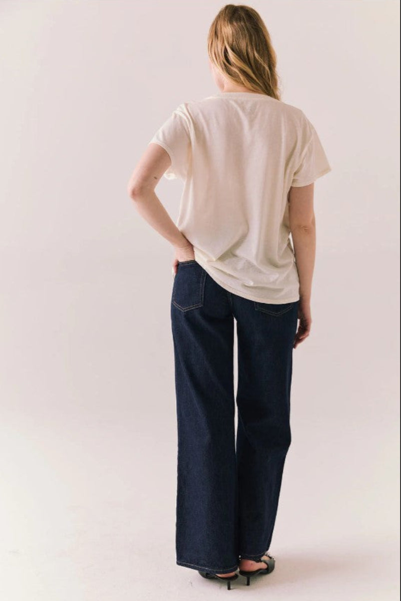 Person wearing a white t-shirt and dark blue jeans on a plain background