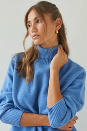 Woman wearing a blue sweater against a plain background