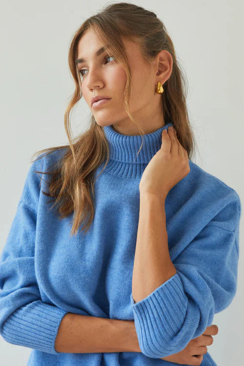 Woman wearing a blue sweater against a plain background