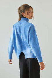 Woman wearing a blue sweater against a plain background