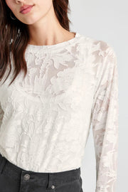 Front view of woman wearing an off white lace-like long sleeve