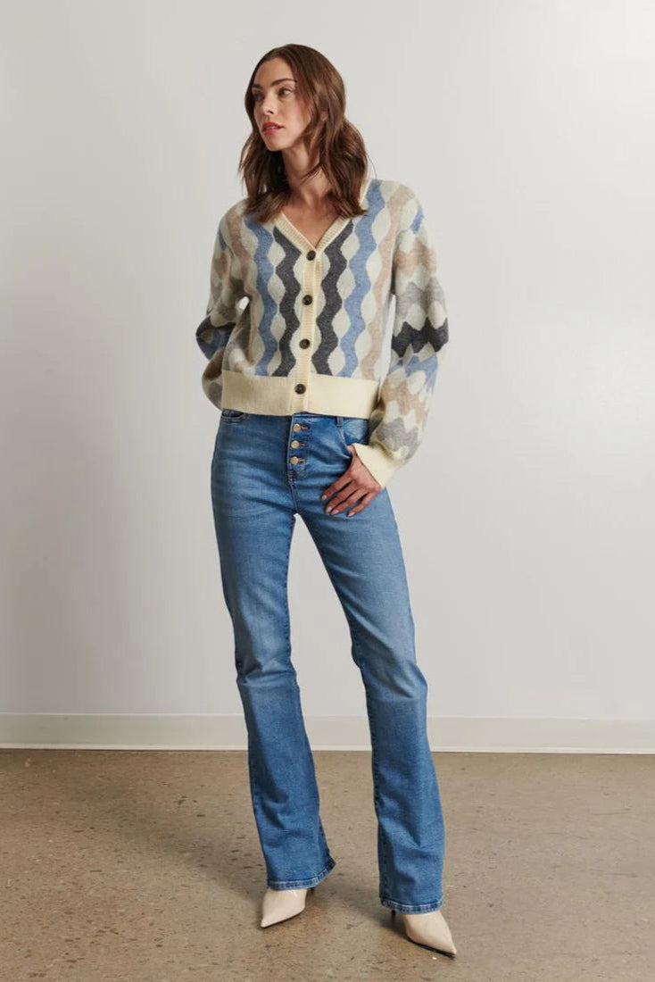Woman wearing a patterned sweater and blue jeans against a plain background