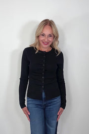 Video of a woman wearing a black rouched front knit top