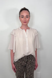 Video of woman wearing an oat coloured light blouse