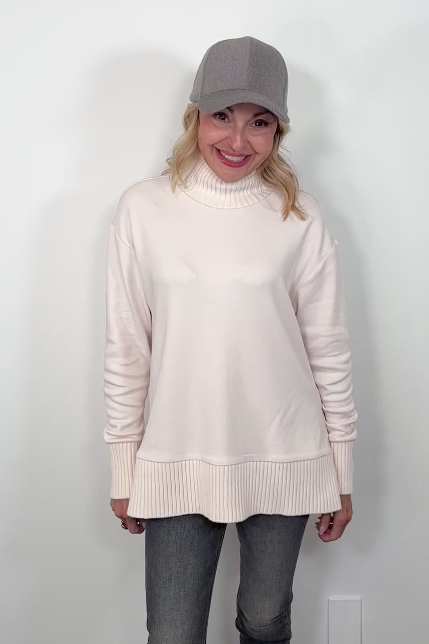 video of a woman wearing a white mock neck sweatshirt