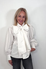 Video of woman wearing a white poplin shirt with a Bow in the neck untucked