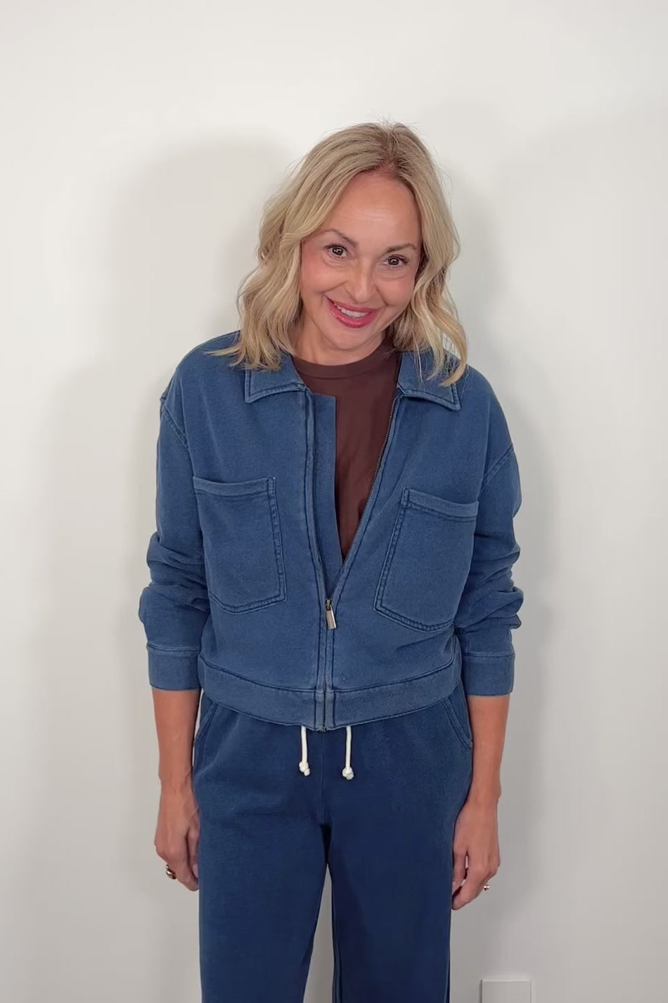 video of a woman wearing a blue jacket and pants against a plain background