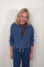 video of a woman wearing a blue jacket and pants against a plain background