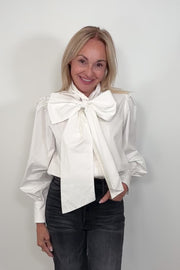 Video of woman wearing a white poplin shirt with a Bow in the neck tucked in
