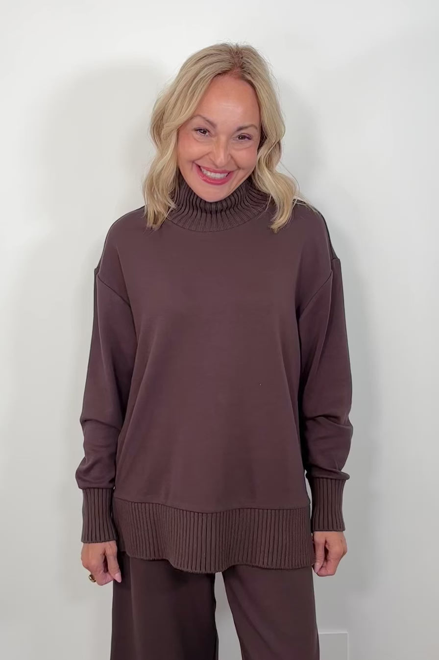Video of a woman wearing a mock-neck sweatshirt
