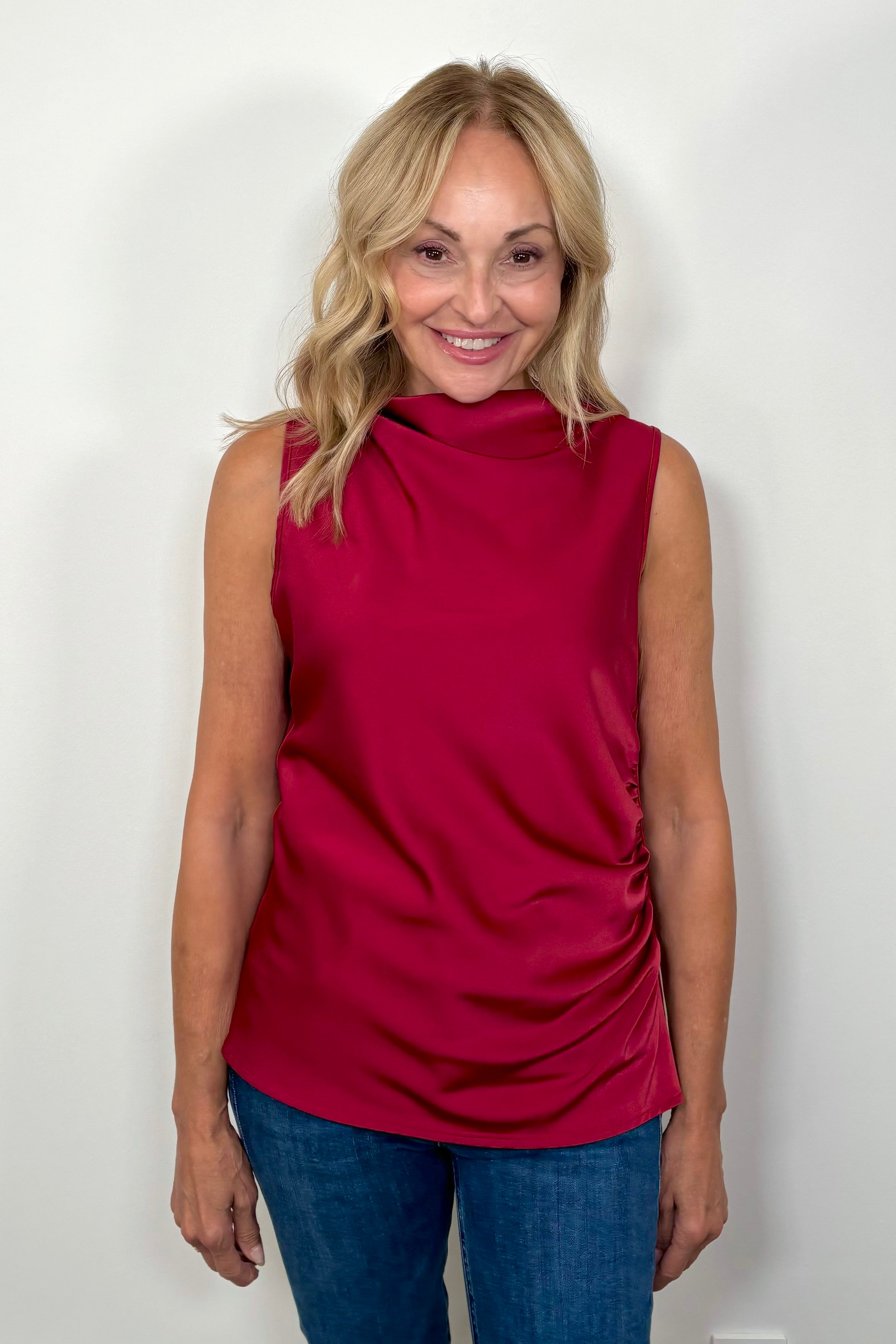 Front facing woman wearing a red rouched sleeveless top