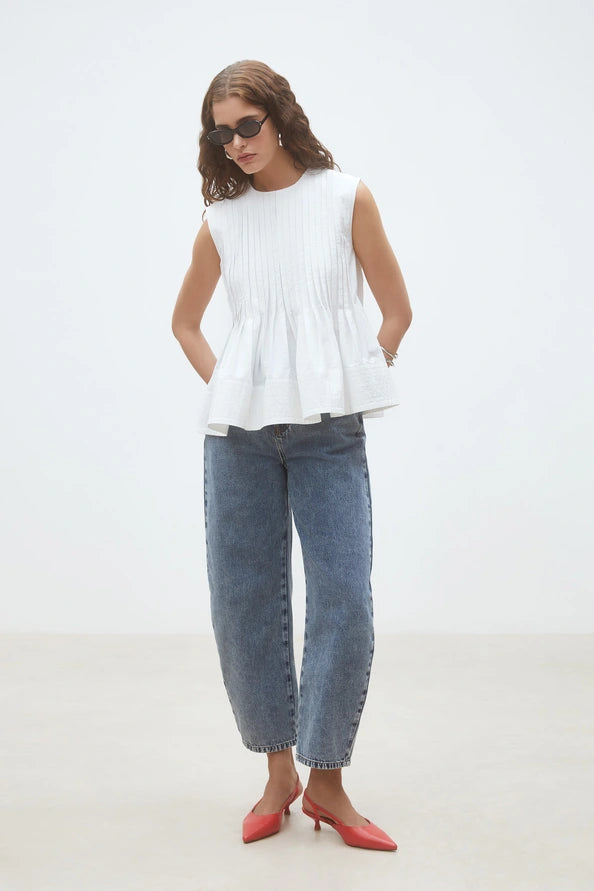 Woman wearing a white sleeveless top, front