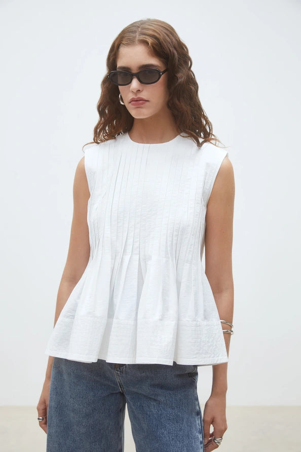 Woman wearing a white sleeveless top, front