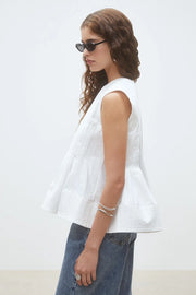 Woman wearing a white sleeveless top, side