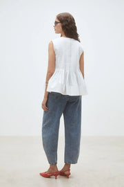 Woman wearing a white sleeveless top, back