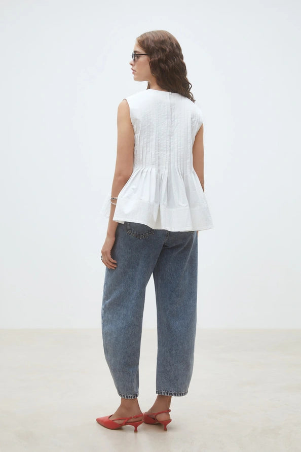 Woman wearing a white sleeveless top, back