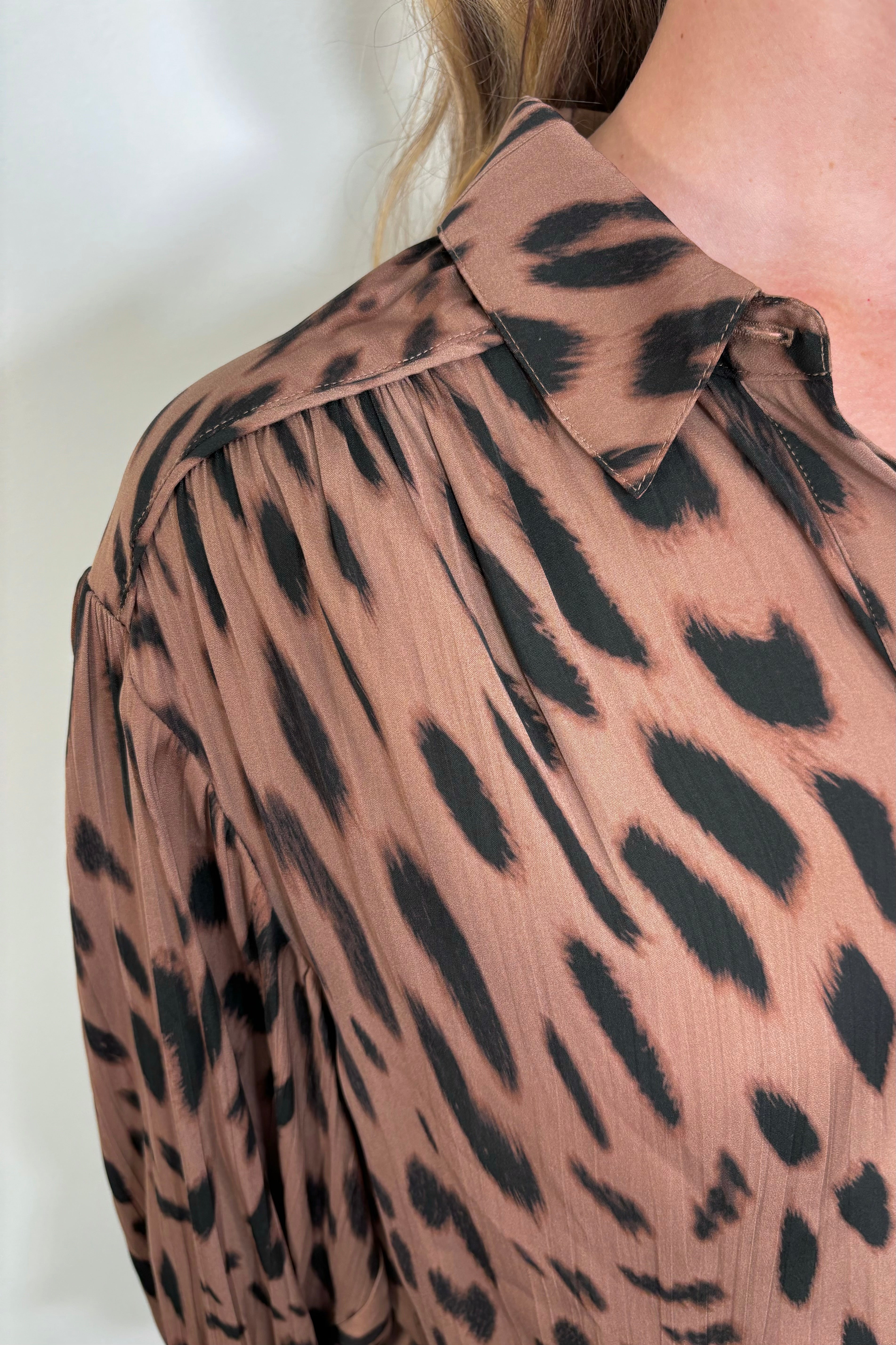 Shoulder Close up of woman wearing a brown printed blouse 