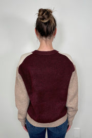 Back view of woman wearing a colour block beige and burgundy cardigan with pockets