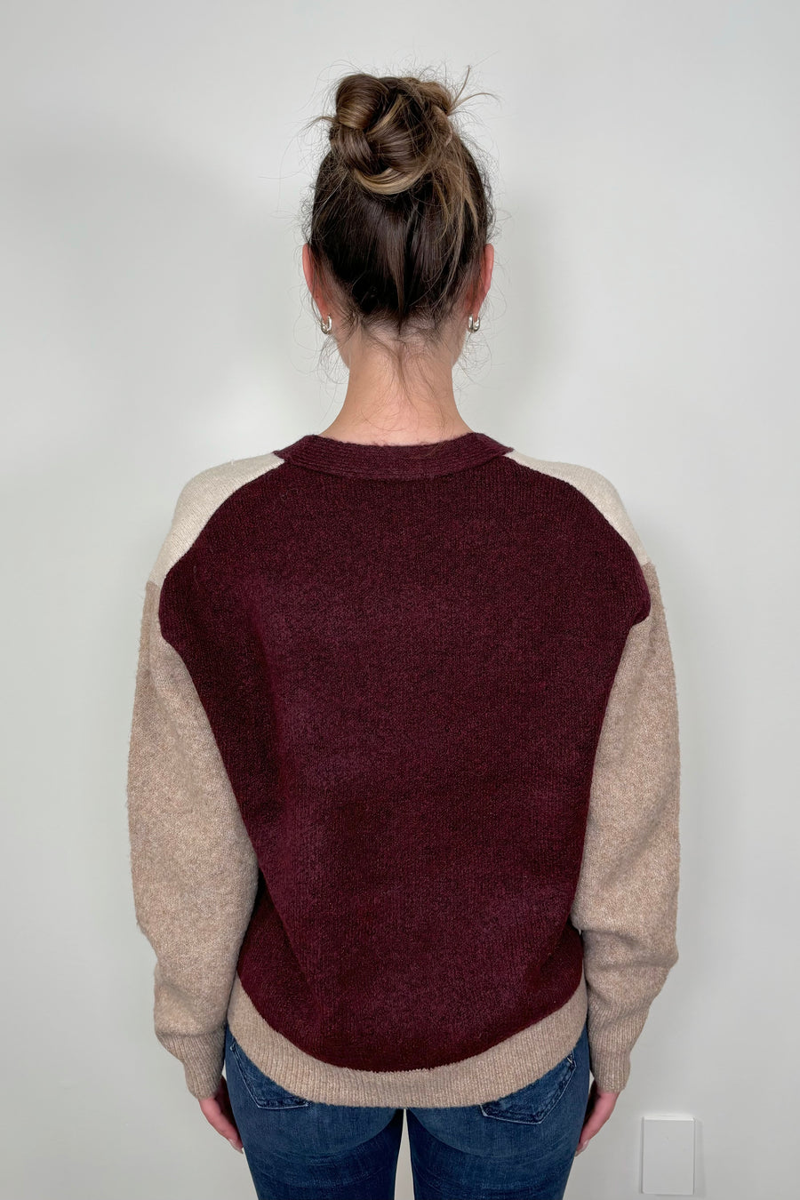Back view of woman wearing a colour block beige and burgundy cardigan with pockets