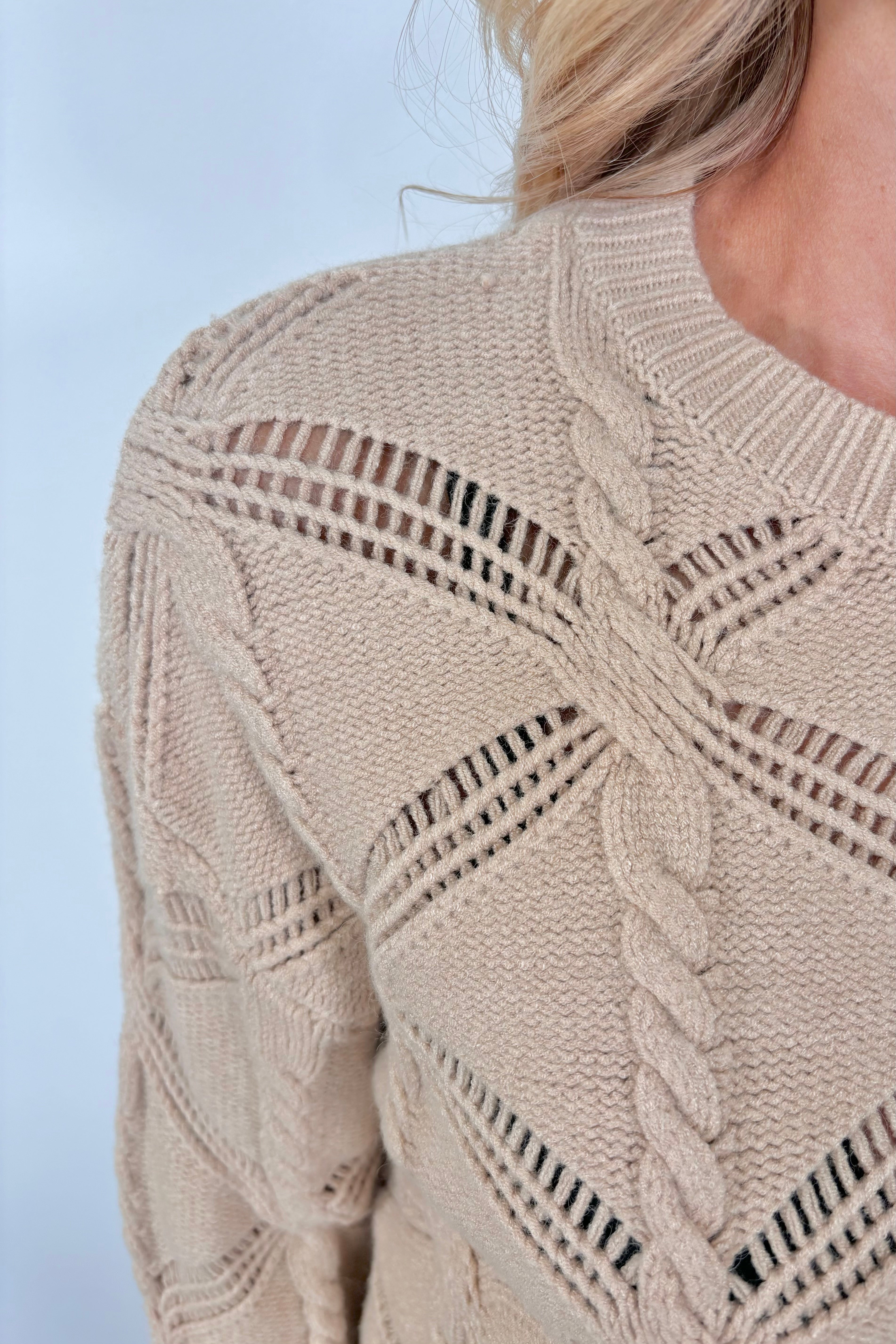 Close up view of a woman wearing a cable knit sweater