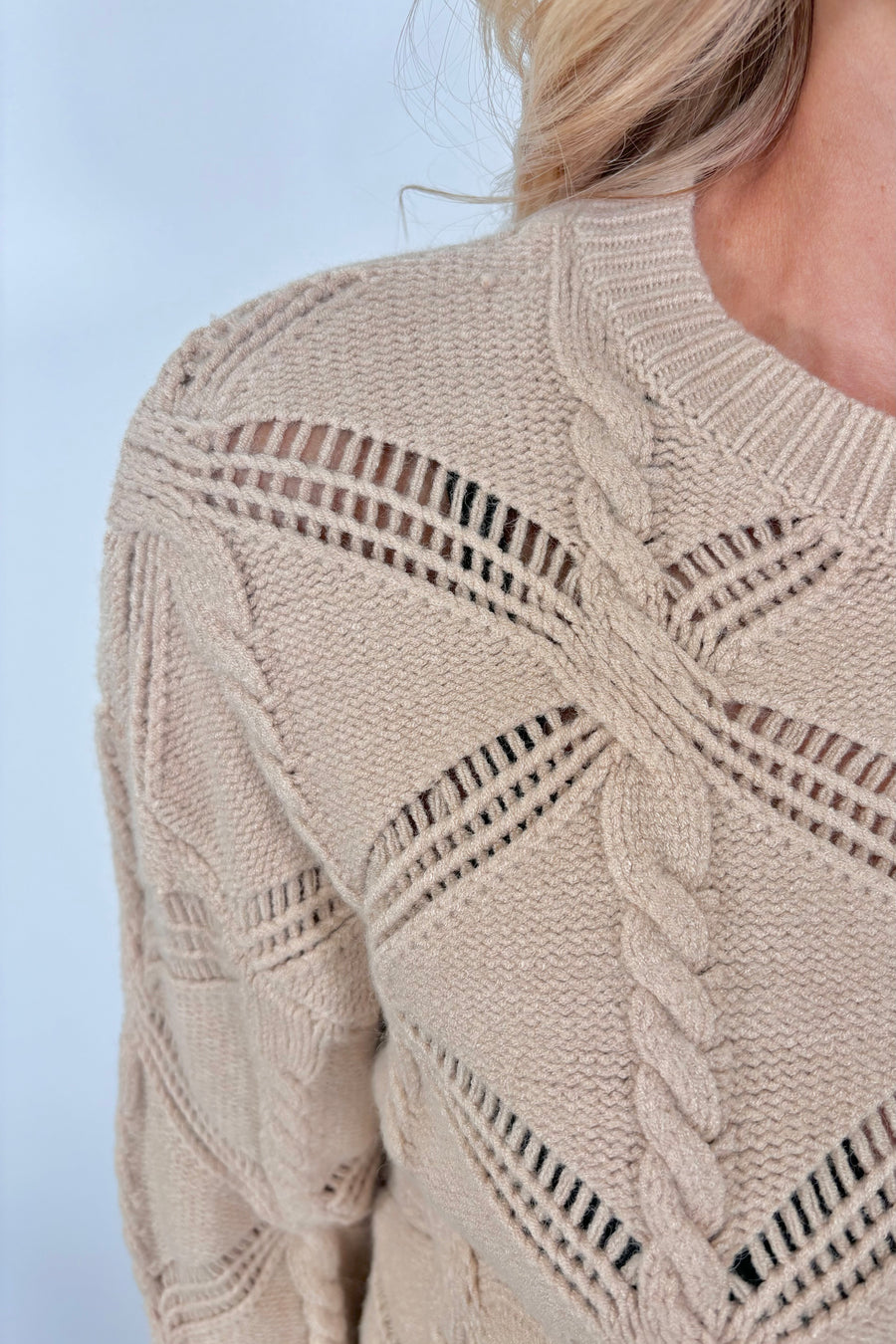 Close up view of a woman wearing a cable knit sweater