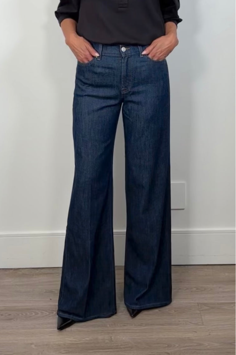 Person wearing blue flared jeans against a plain background