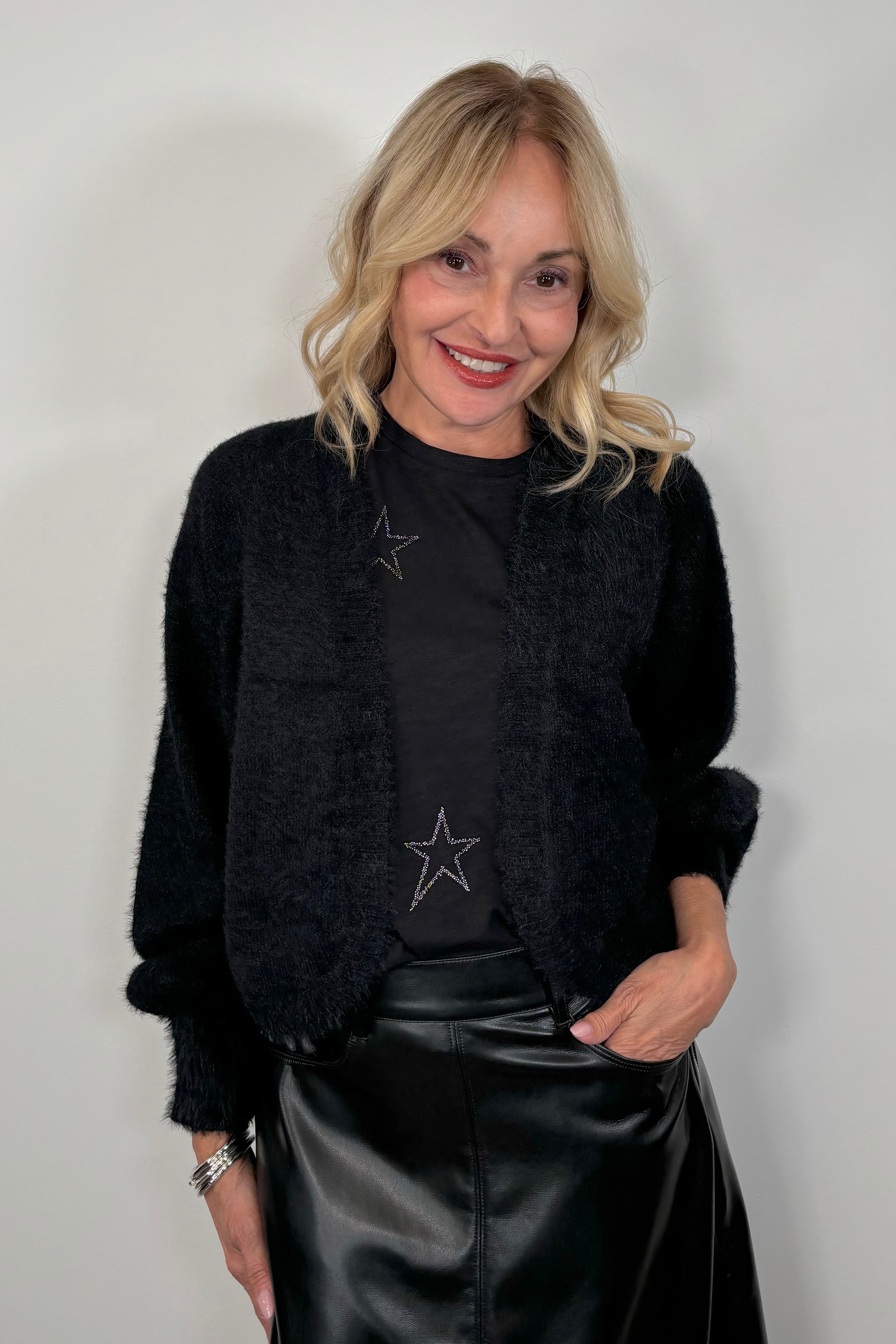 woman wearing a black shrug cardigan over a star print tee