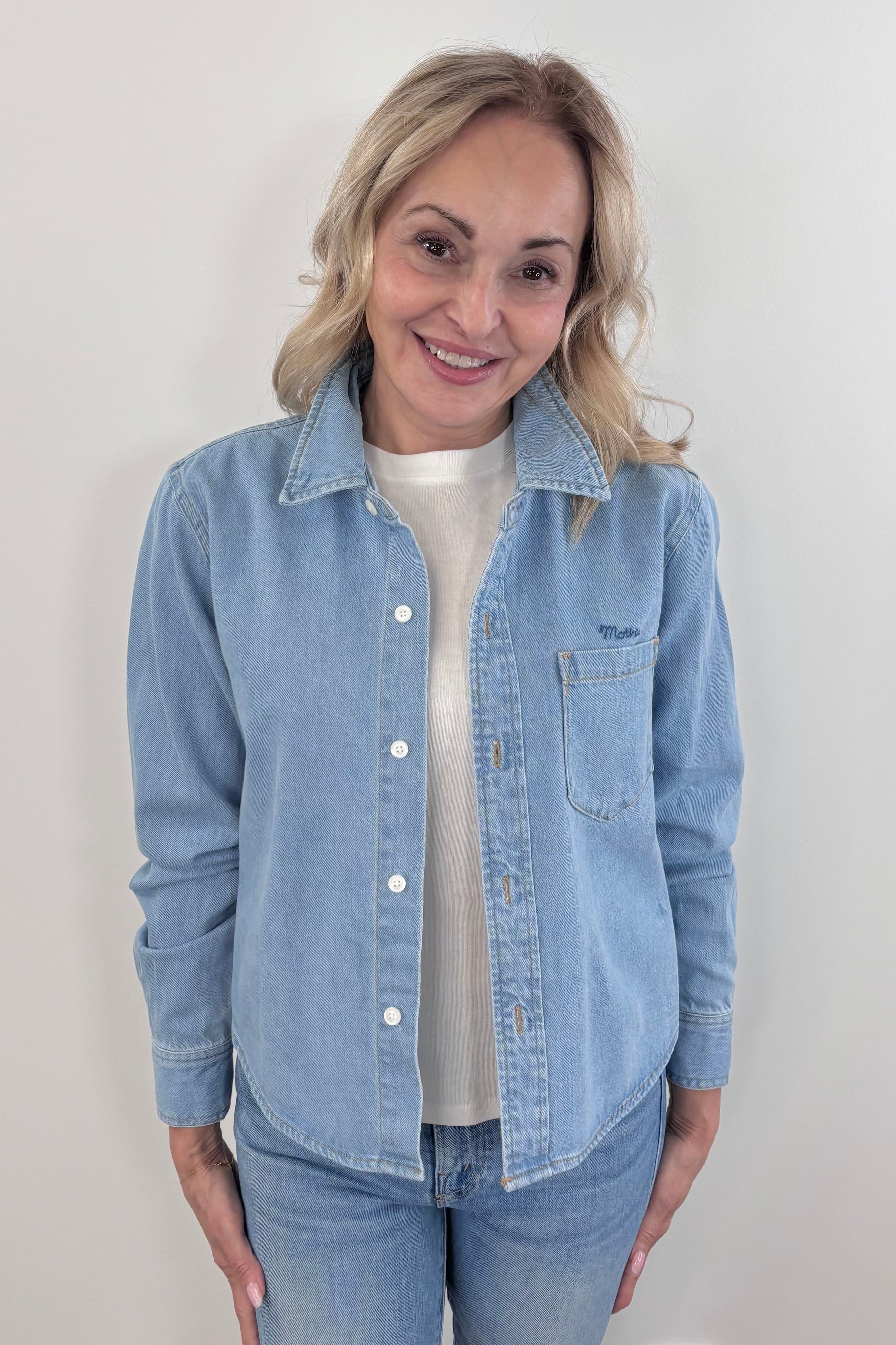 Close up of a woman wearing a light wash denim collared button up with side pocket