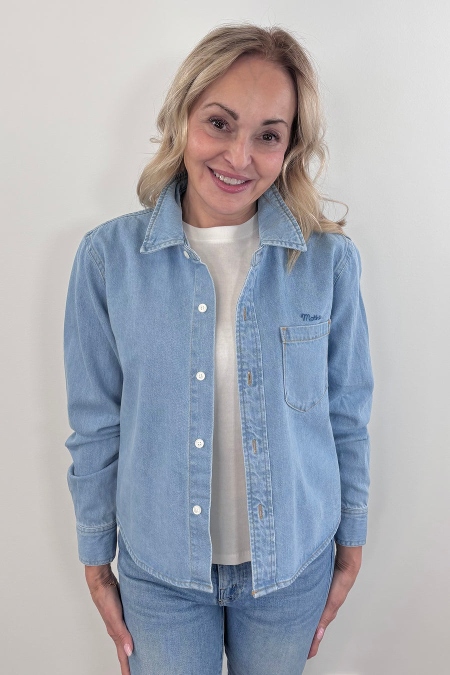 Close up of a woman wearing a light wash denim collared button up with side pocket