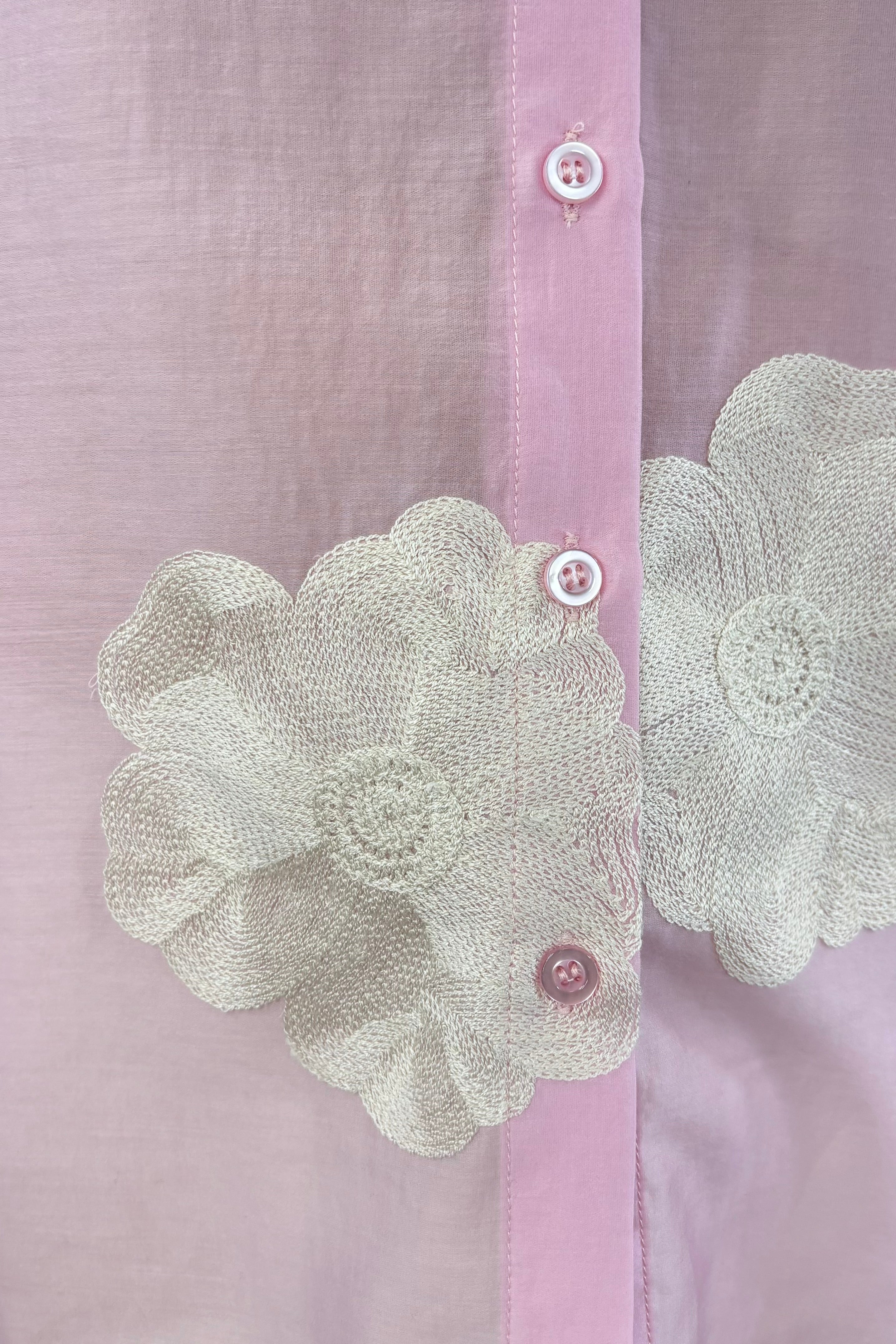 Close up of Woman wearing a light pink blouse with embroidered white floral print allover