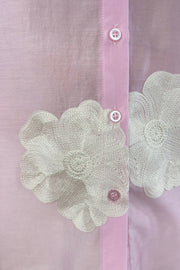 Close up of Woman wearing a light pink blouse with embroidered white floral print allover
