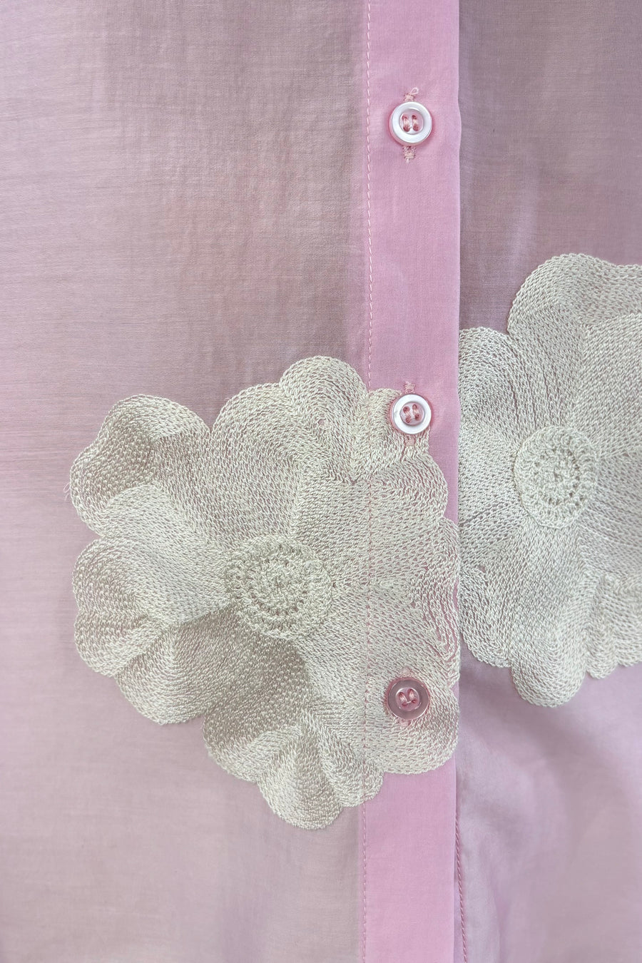 Close up of Woman wearing a light pink blouse with embroidered white floral print allover