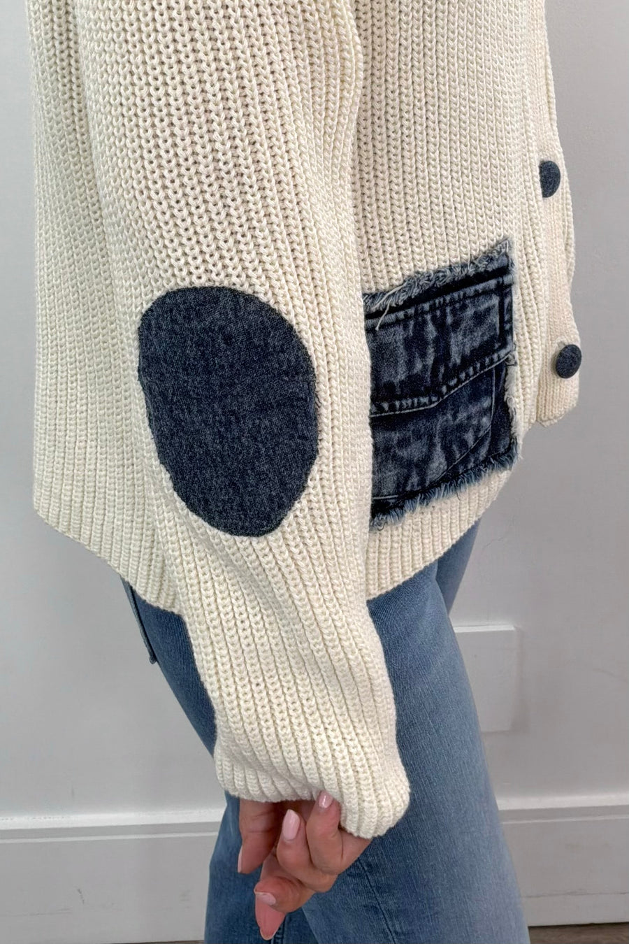 Side close up of Woman wearing a cream knit cardigan with denim pocket detail